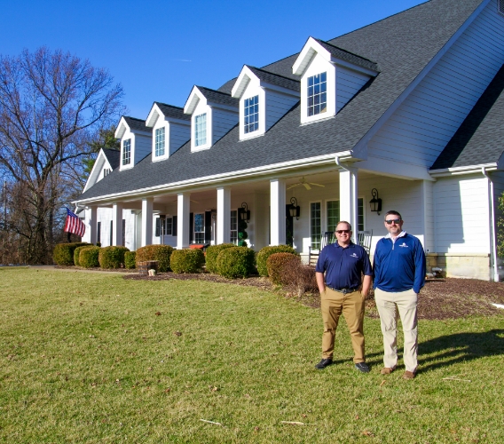 Rob Eilermann and Chris Jones of Saint Louis Residential Roofing pose in front of a home.