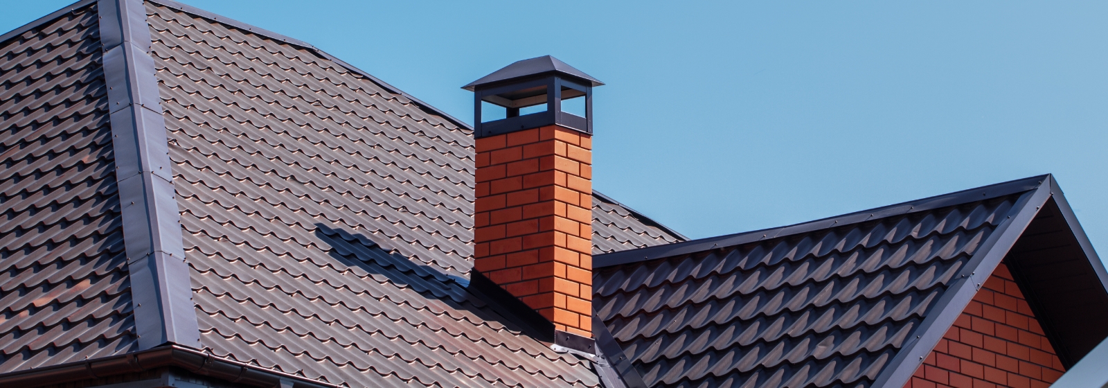 A roof with new shingles and a red brick chimney.