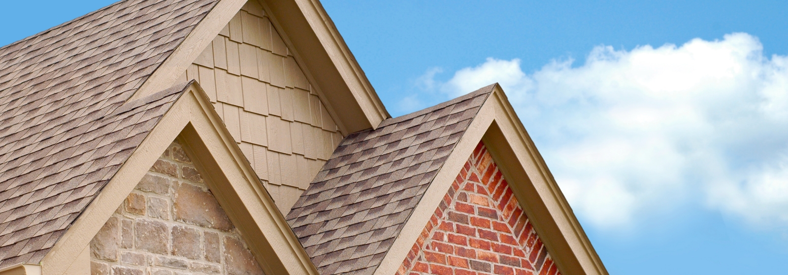 A photo of a three-pointed roof with brown shingles and red brick